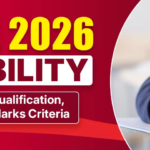 A promotional graphic for "IIT JEE 2026 ELIGIBILITY" set against a red and white background. On the left, large yellow text reads "IIT JEE 2026," followed by "ELIGIBILITY" in bold maroon text inside a white box. Below this, a smaller maroon box contains the text "Age Limit, Qualification, Attempts & Marks Criteria." On the right, a close-up shows a person's hand writing on a piece of paper with a clear pen.